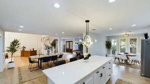 Una cocina moderna con una isla central, armarios blancos y una araña.