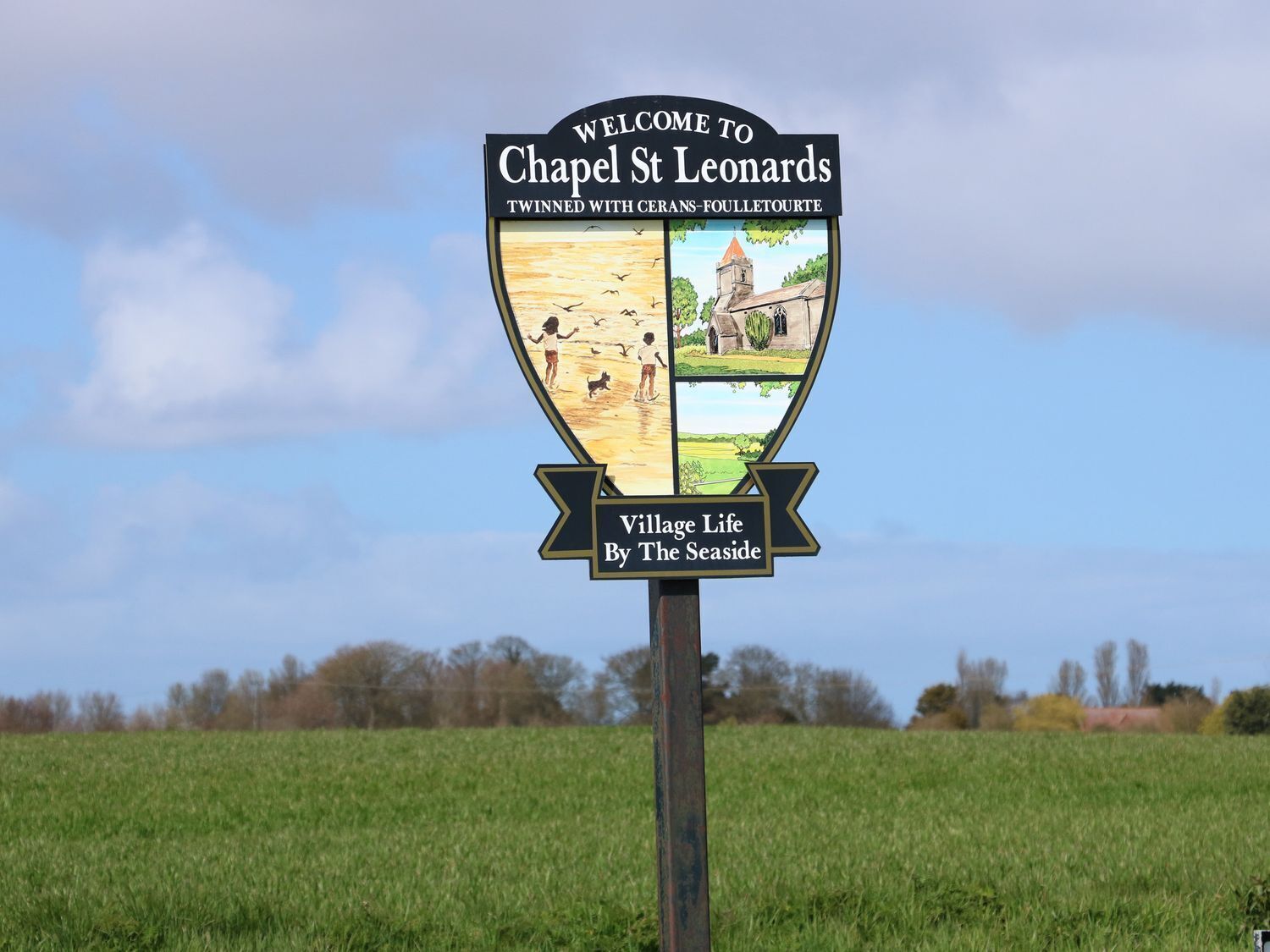 A welcome sign for Chapel St Leonard with twin town information and a depiction of village life by the seaside.