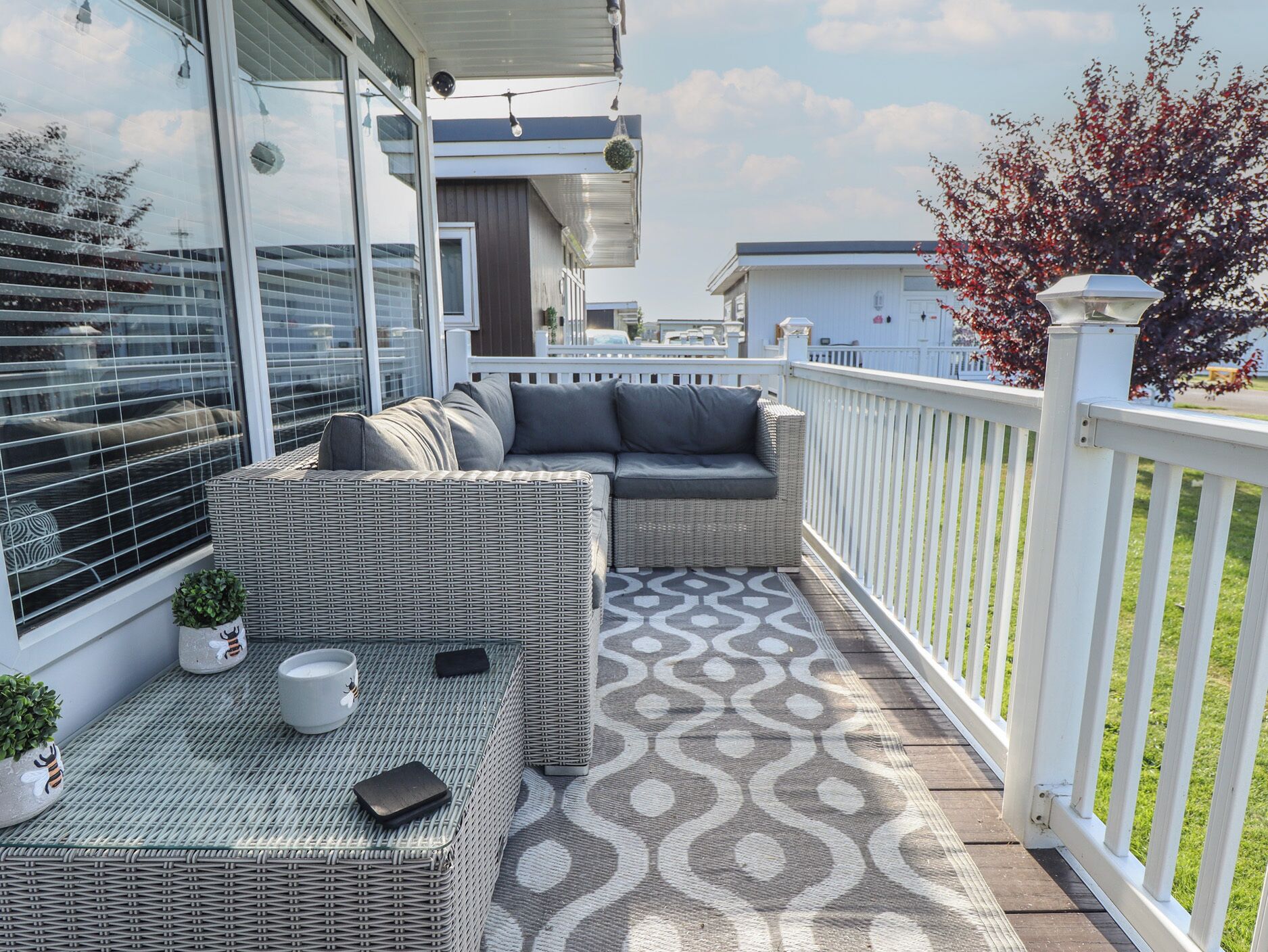 A covered outdoor seating area with wicker furniture and a patterned rug.