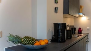 A kitchen with a bowl of fruit on the counter, a coffee maker, and a red kettle. - Arbio I Duxen Apartments Hagenbeck Zoo (Hamburg)