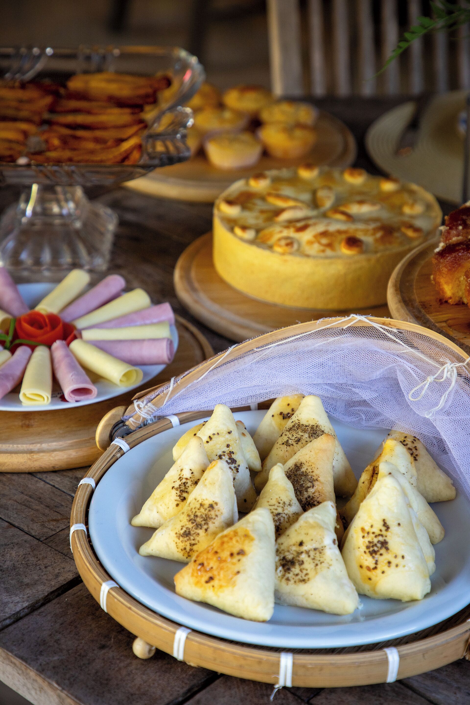 Uma mesa com diversos alimentos, incluindo samosas, um bolo e outras sobremesas.