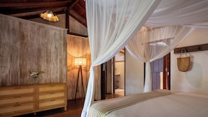A bedroom with a canopy bed, wooden furniture, and a wall-mounted lamp. - Pousada Hibisco (Porto Seguro)