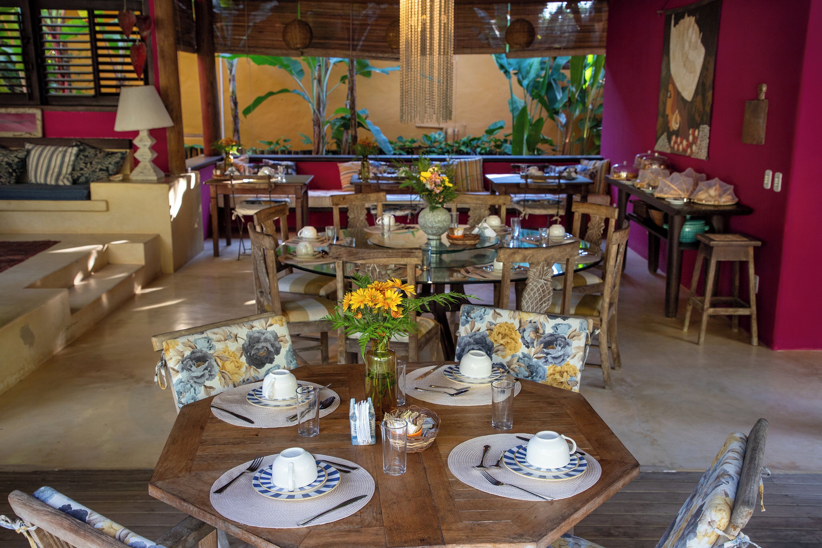 Un comedor con mesas redondas, sillas y un arreglo floral central.