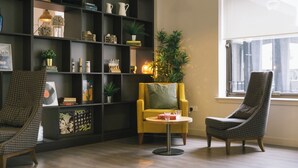 A modern living room with a bookshelf, two armchairs, a small round table, and a large window. - Student Only Bath Street (Glasgow)