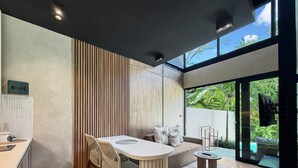 A modern kitchen with a dining area, a sofa, and a view of a swimming pool.