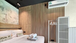 A hotel room with a bed, a wall-mounted air conditioner, and a radiator.