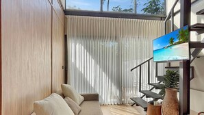 A modern living room with a sofa, a TV, and a staircase. - Luxury Private Pool Loft Canggu (Canggu)
