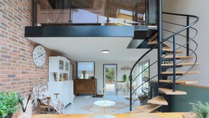 A modern interior with a spiral staircase, a brick wall, and a dining area with a wooden table.