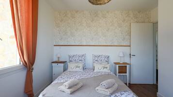 A bedroom with a bed, two nightstands, a door, and a window with curtains.