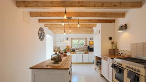 A kitchen with wooden beams, a central island, and a stove.