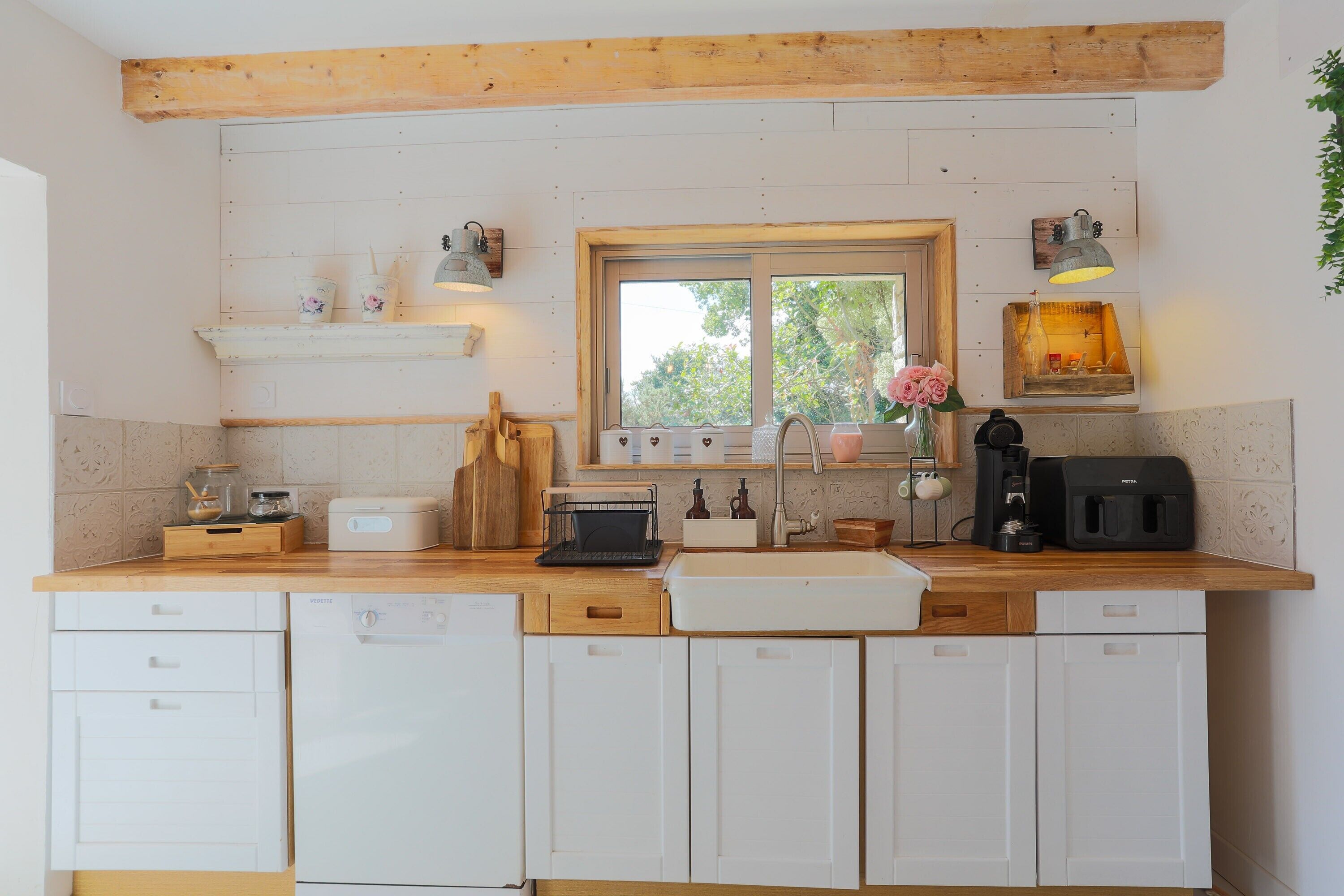 Una cocina con encimeras de madera, armarios blancos, una ventana y diversos electrodomésticos.