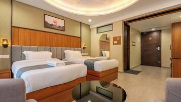 A hotel room with two beds, a round table, and a view of the hallway.