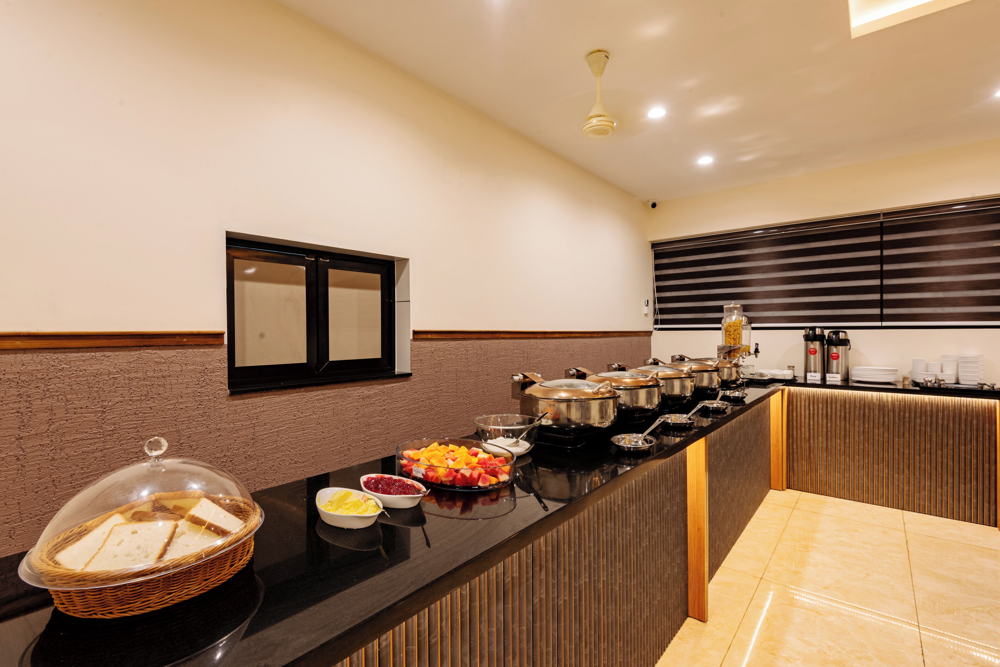 A buffet setup with various food items and a basket of bread.
