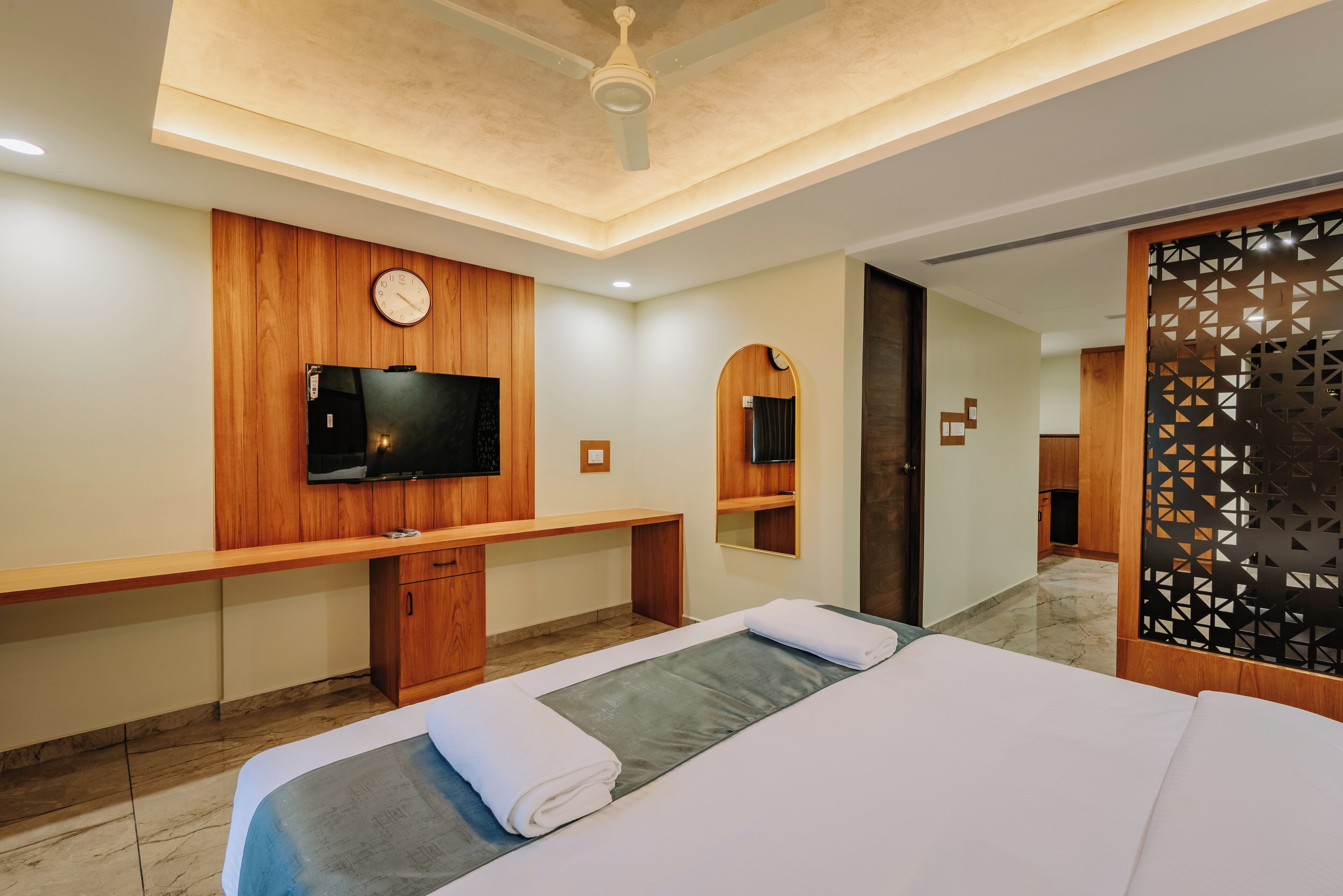 A hotel room with a bed, a desk, a TV, and a mirror.