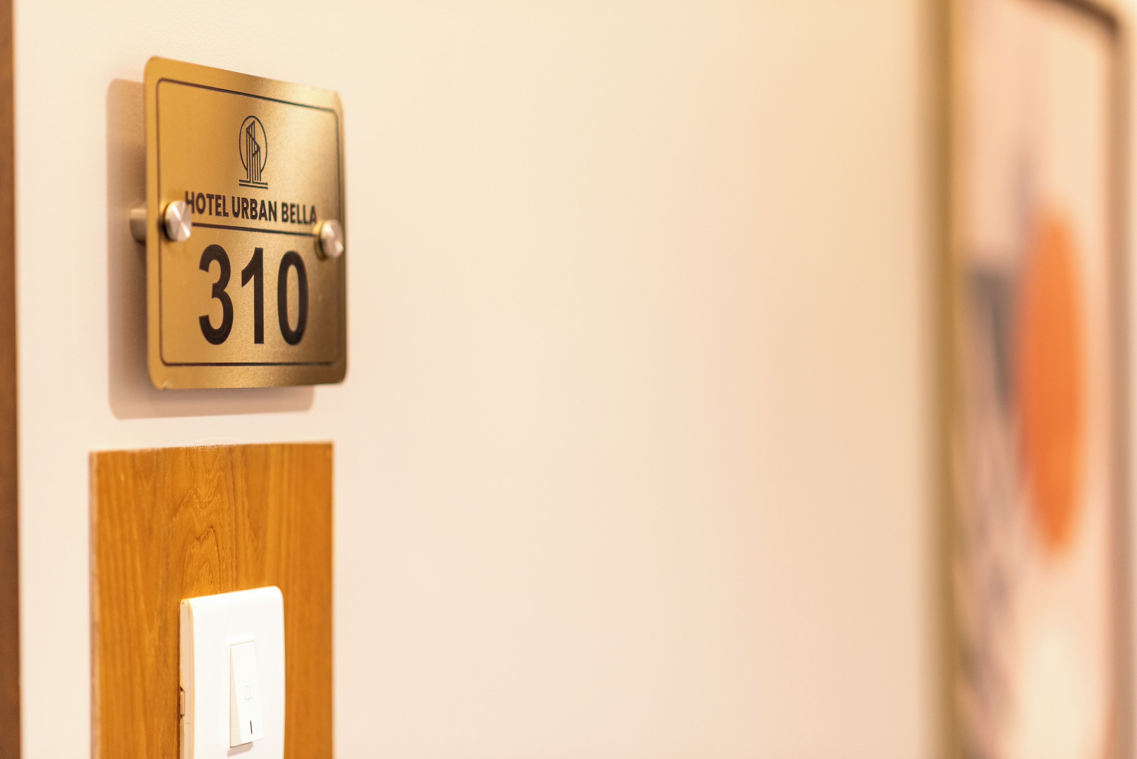 A hotel room door with a sign above it indicating the room number 310 and the name "Hotel Urban Bella".