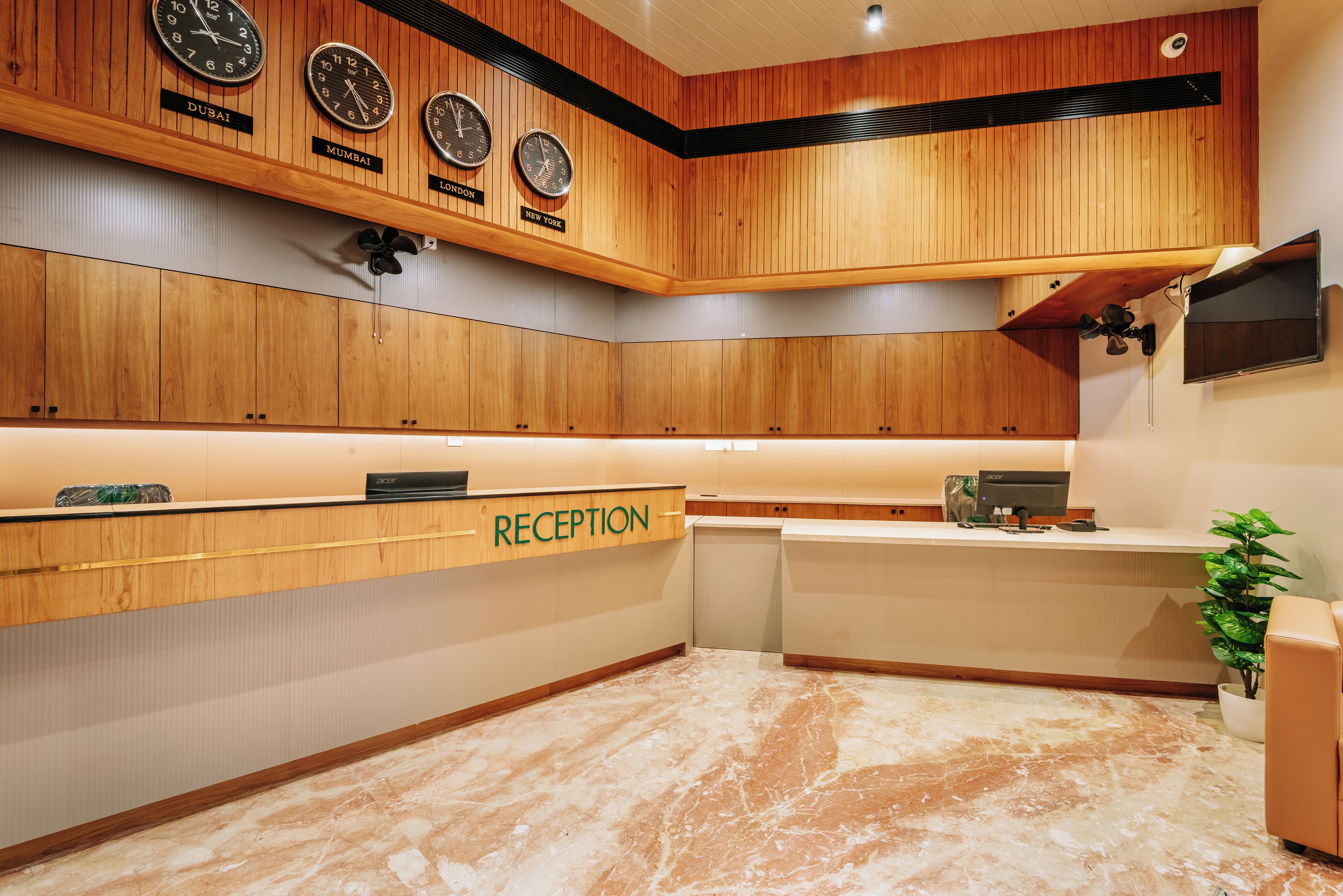 A reception area with wooden paneling, clocks displaying times from Dubai, Mumbai, London, and New York, and a reception desk labeled "RECEPTION".
