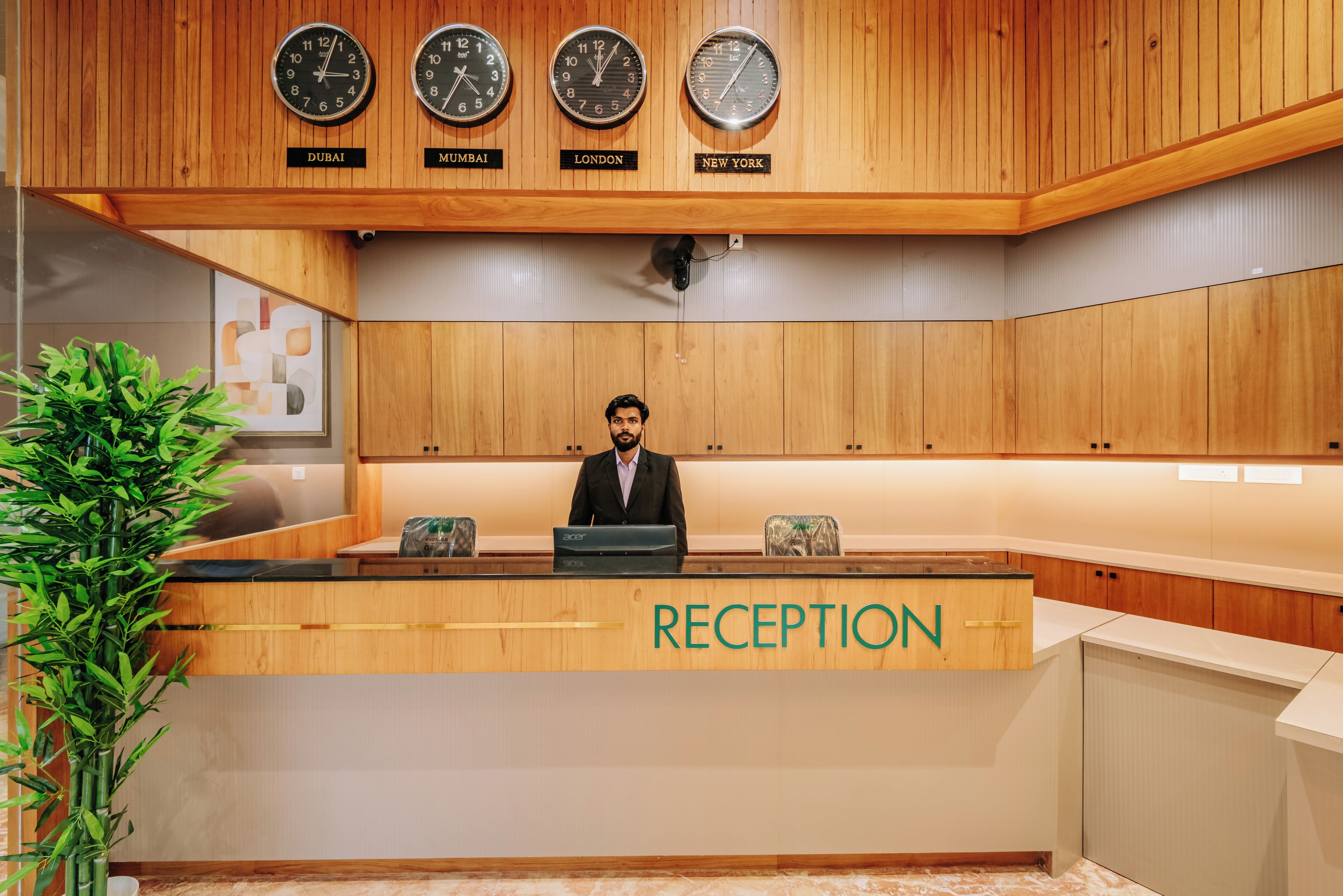 A reception desk with clocks displaying times for Dubai, Mumbai, London, and New York.