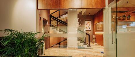 Un interior moderno con una escalera, paneles de madera y una alfombra roja que conduce a una puerta de vidrio.