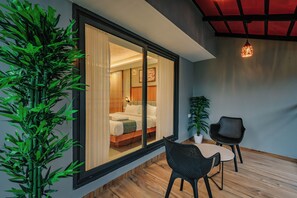 Una habitación moderna con un amplio ventanal, una cama, una mesita pequeña y dos sillas.
