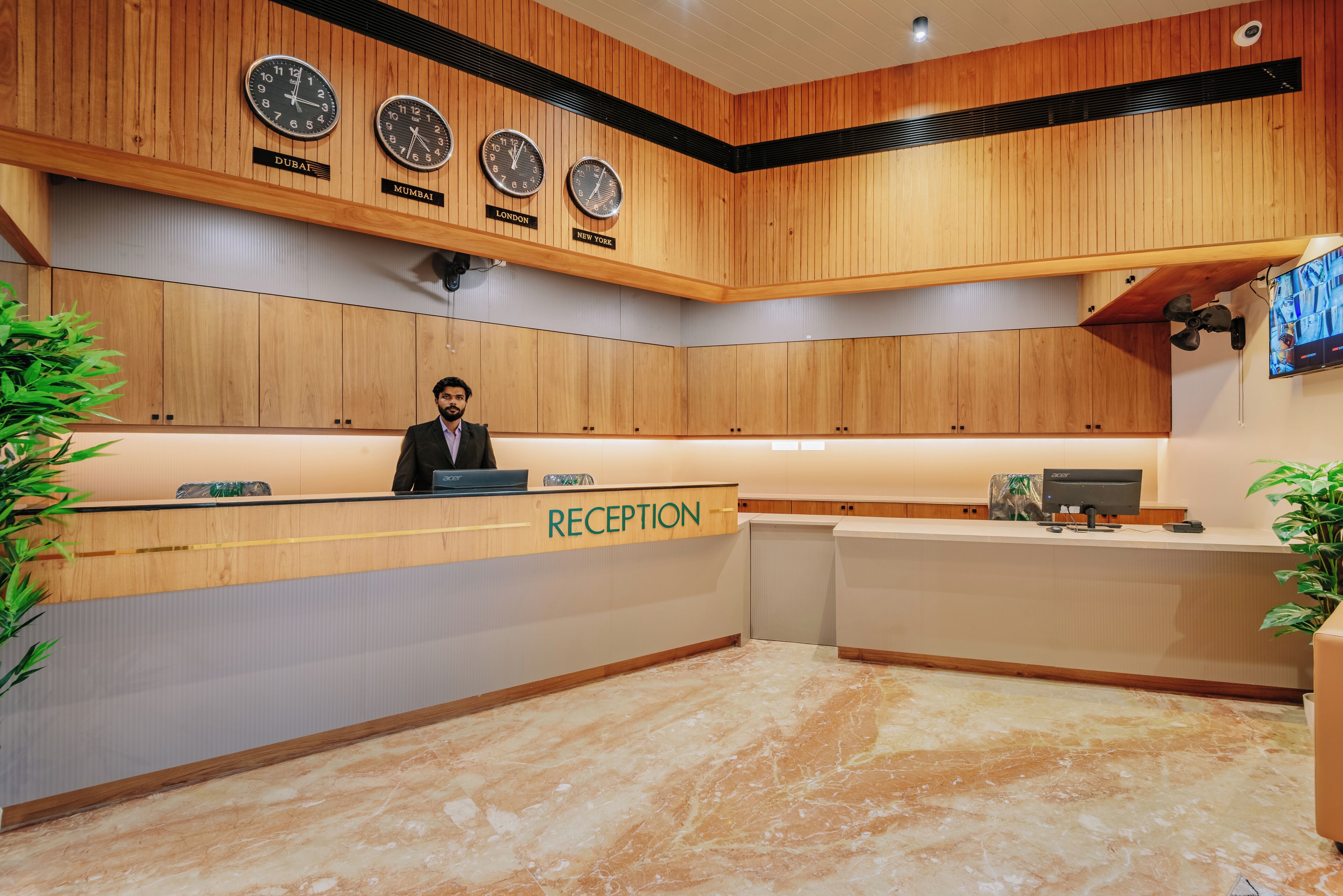 A reception area with wooden paneling, clocks indicating different cities, a reception desk, and a television.