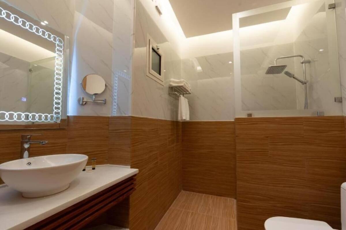 A modern bathroom with a large mirror, a sink, and a shower area.