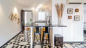Eine moderne Küche mit schwarzem Arbeitsplatz, zwei gelben Barhocker und einem fußboden mit geometrischem Muster.