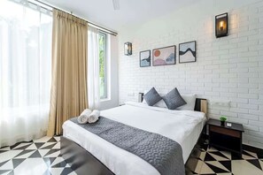 A hotel room with a large bed, a window with curtains, a white brick wall, and artwork. - Coastal Grandeur by Da Alohas (Nerul)