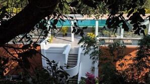 Eine Treppe führt zu einem weißen Gebäude, im Hintergrund ist ein Pool zu sehen.