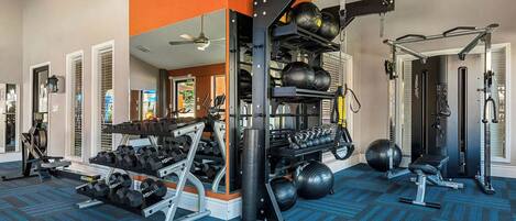Une salle de sport équipée de divers appareils d’entraînement, notamment des haltères, des kettlebells et un support à squats.