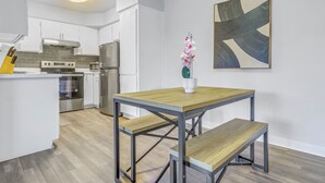 A modern kitchen with white cabinets, stainless steel appliances, and a wooden dining table with benches.