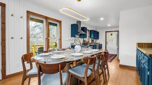 A dining area with a round table set for six, wooden chairs, and a modern pendant light. - Luxury•5 Kings•MTN Views and Lake Access•FirePit•EVCharger•PoolTable (Lake Lure)