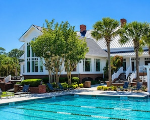 A pool with lane dividers, a white building with a brick base, and palm trees. - Lux|King Bed|Free Golf|Heated Pool|Bikes|Parris Is (Okatie)