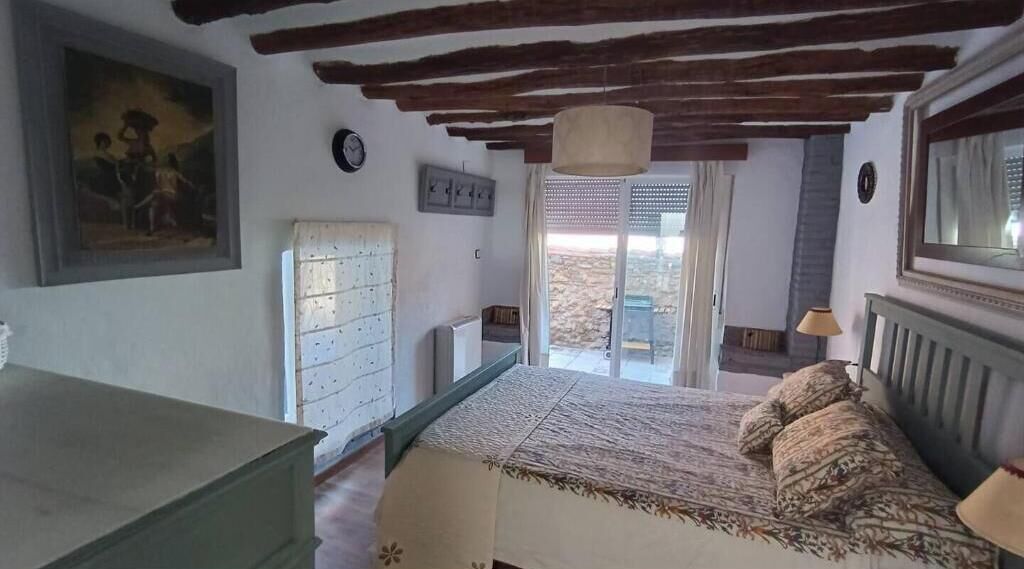 Une chambre à coucher avec un lit, une commode, un tableau, une horloge et une fenêtre donnant sur un beau paysage.