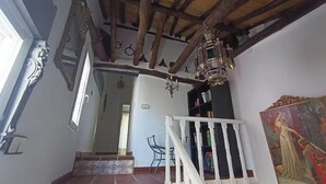 A staircase with a white railing leading to a landing. There is a chandelier hanging from the ceiling, and a painting on the wall. - Eras House (Nigüelas)