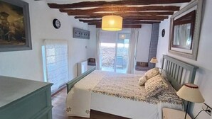 A bedroom with a bed, a nightstand, a lamp, a dresser, and a window with a view. - Eras House (Nigüelas)