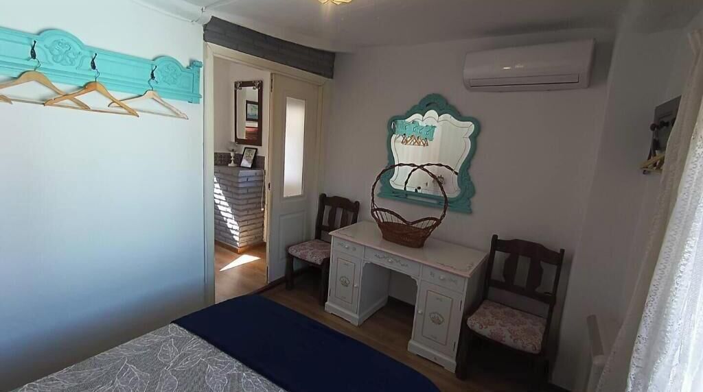 Une chambre à coucher comprenant un lit, un bureau, deux chaises, un panier et un climatiseur fixé au mur.