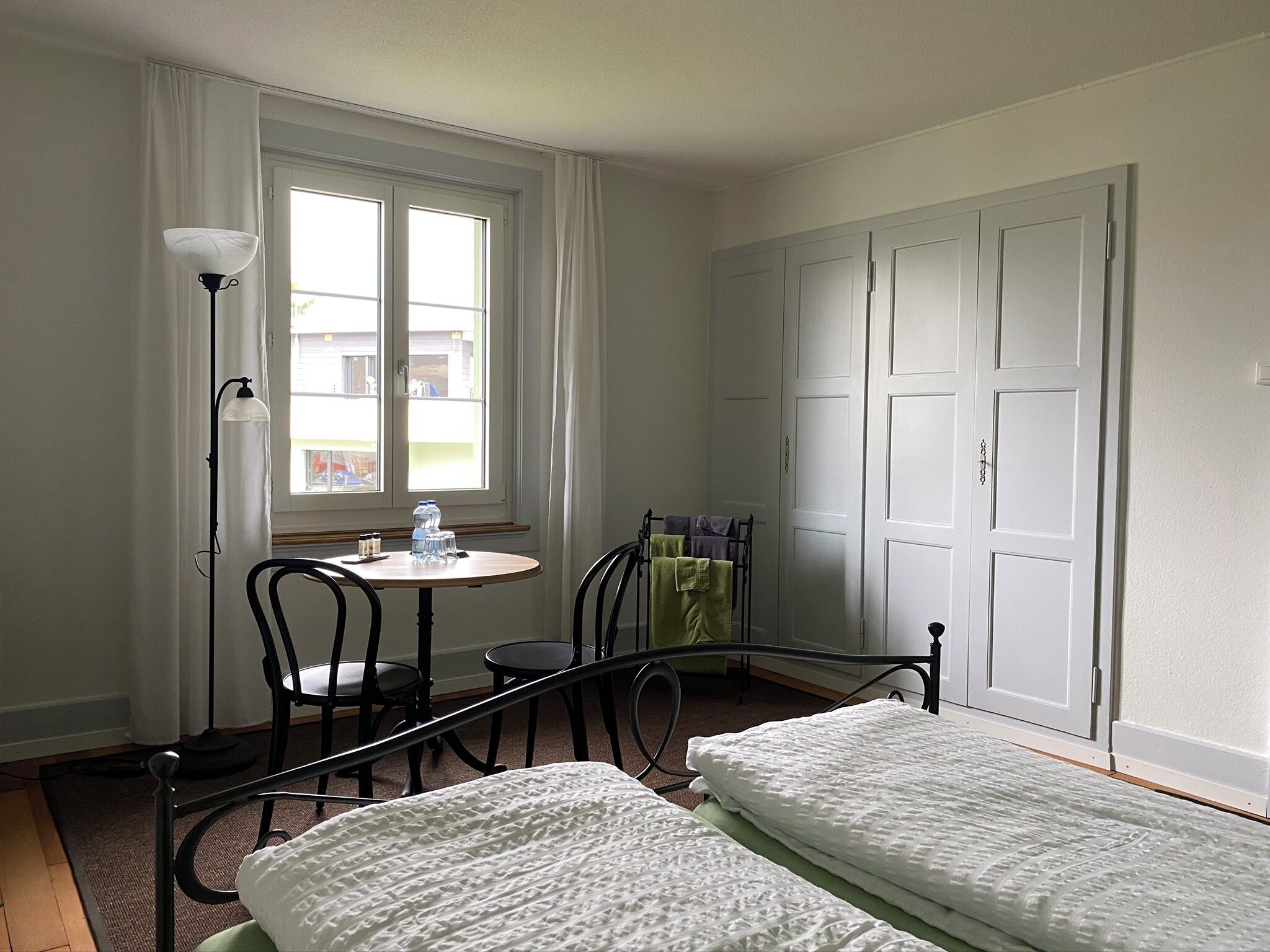 Une pièce comprenant un lit, une table, des chaises, une lampe et une armoire.