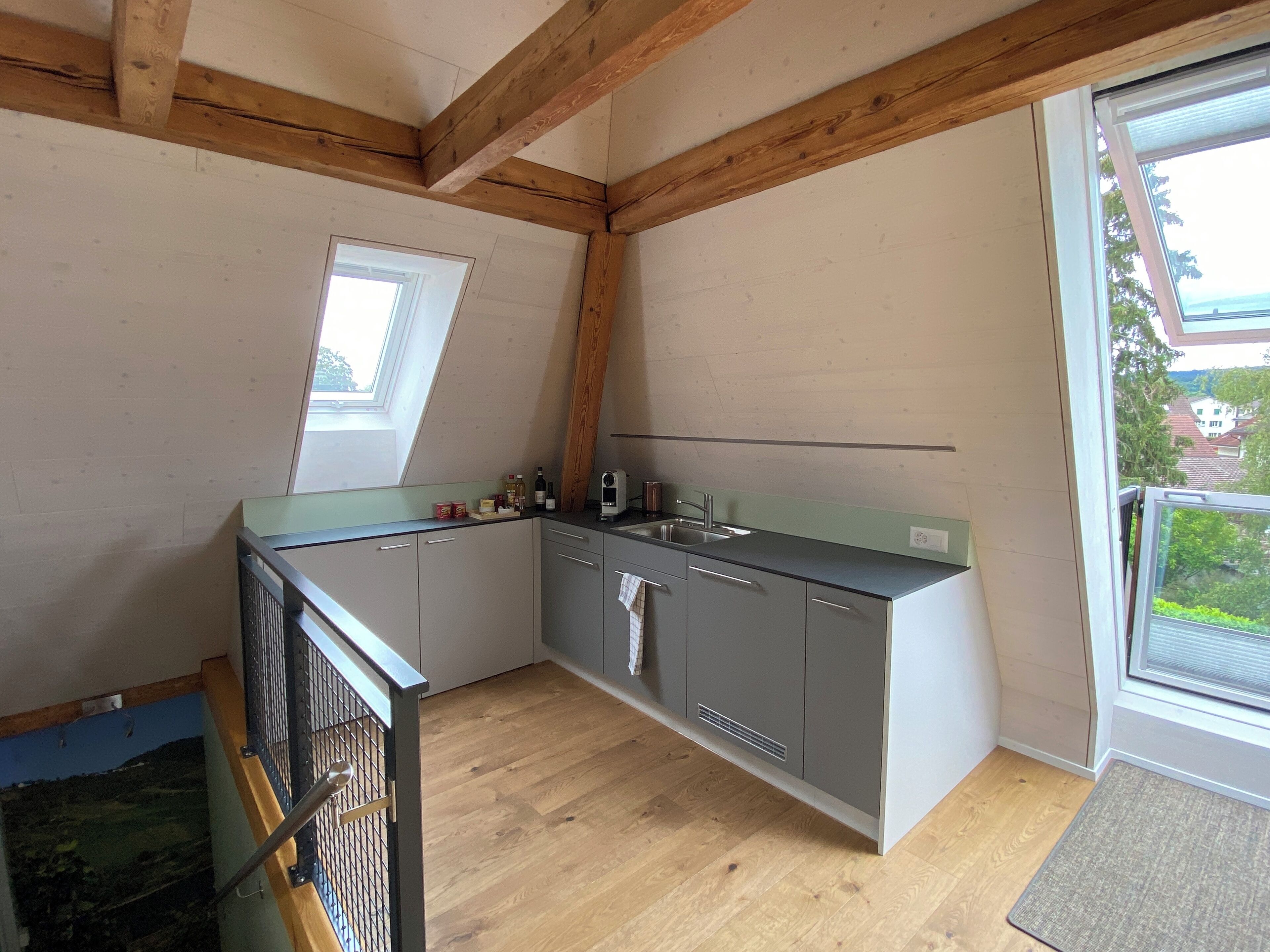 A compact kitchen with a wooden ceiling, a small window, and a view of the outside.