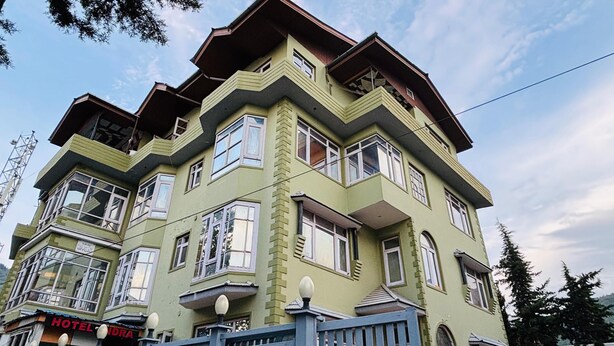 A multi-story hotel with a green facade, multiple windows, and a visible sign reading "HOTEL". - Hotel Indra (Srinagar)