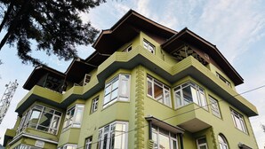 A multi-story building with a green facade, multiple windows, and a corner balcony. - Hotel Indra (Srinagar)