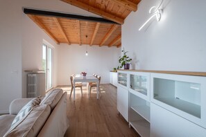 Eine moderne Küche mit Holzbalken, einem Essbereich mit Tisch und Stühlen sowie einem weißen Schrank mit Glastüren.