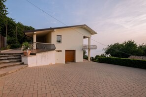 Una casa moderna con techo plano, un pequeño porche y un camino de entrada pavimentado.