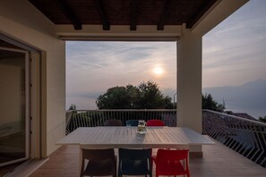 Un balcón con mesa y sillas, con vistas panorámicas al mar y las montañas.