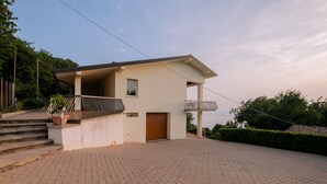 A modern house with a flat roof, a small porch, and a paved driveway.