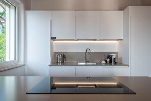 A modern kitchen with a stainless steel sink, a kettle, and a coffee machine.