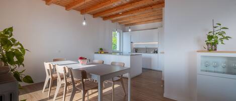 A modern kitchen with white cabinets and a wooden ceiling.