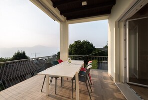 Un balcón con mesa y sillas, con vistas a un paisaje montañoso.