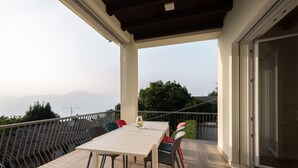 A balcony with a table and chairs, overlooking a mountainous landscape.