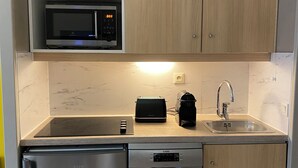 Cocina compacta con microondas, tostadora, cafetera, pileta y lavavajillas.