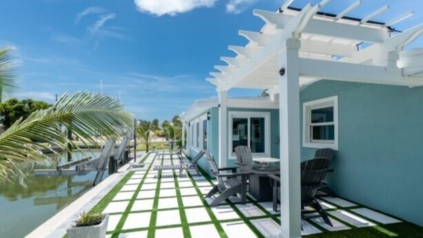 Une terrasse couverte avec un sol à carreaux, une piscine et une pergola.